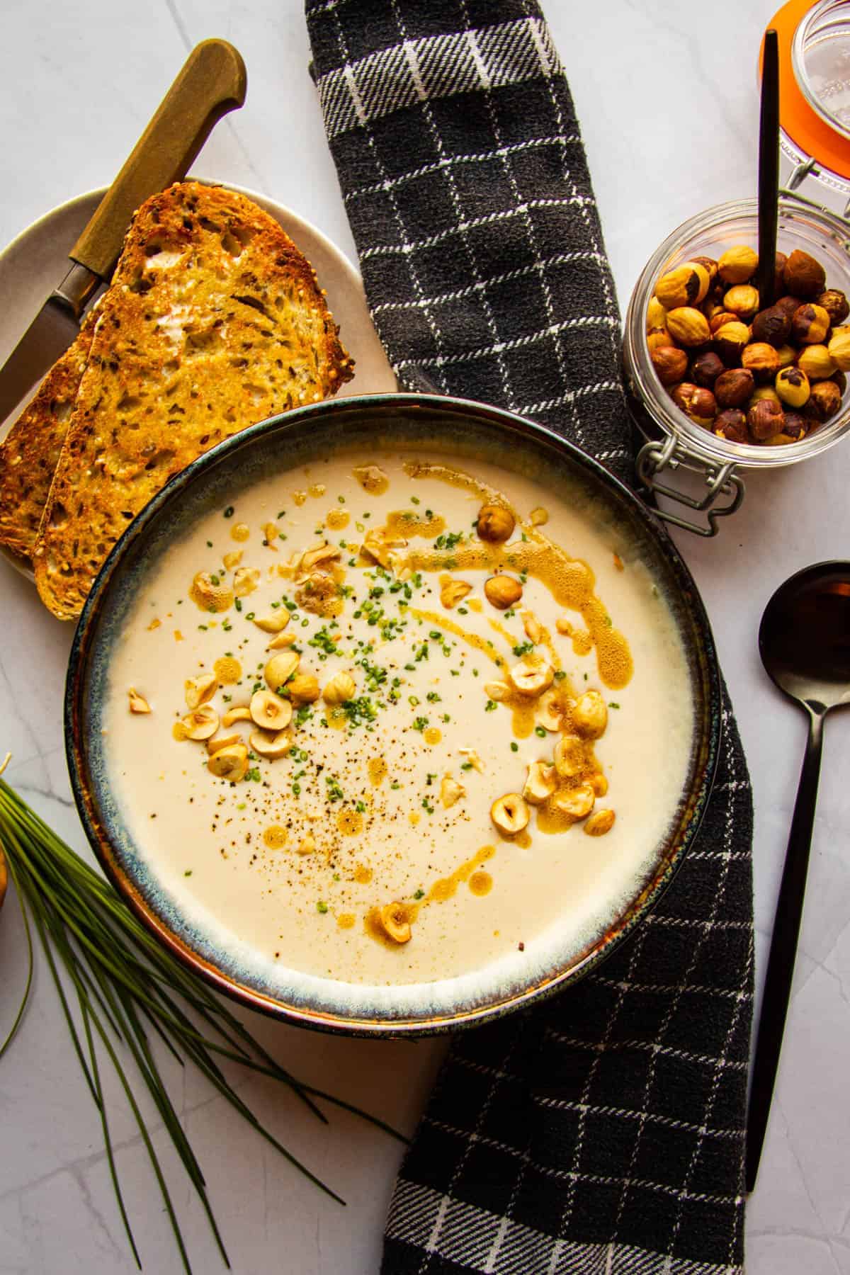 White asparagus soup with hazelnuts and bread on the side.