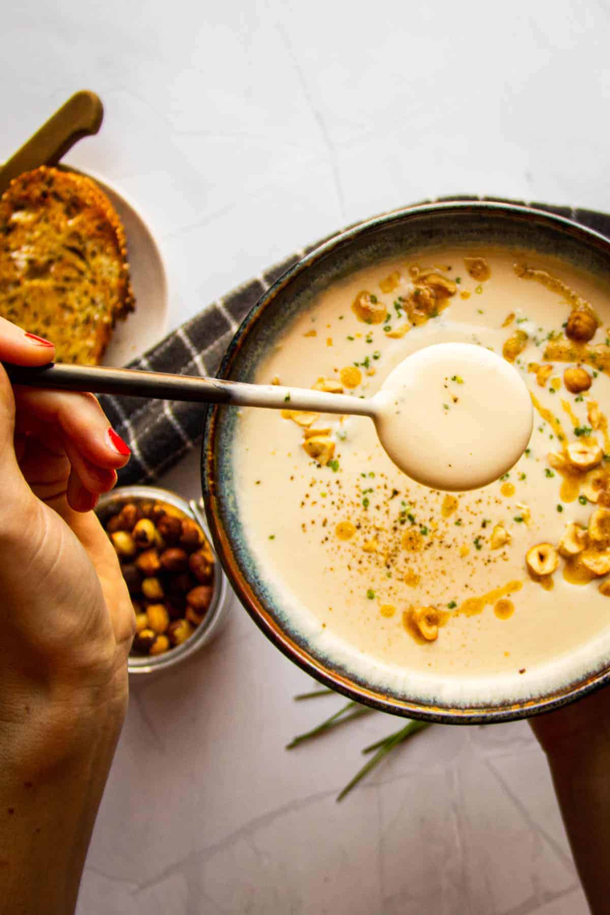 White asparagus soup in a bowl with a spoon.