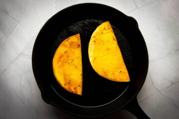Frying the tacos in a cast iron pan.