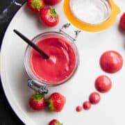 strawberry puree in a mason jar with dots of the puree on the side