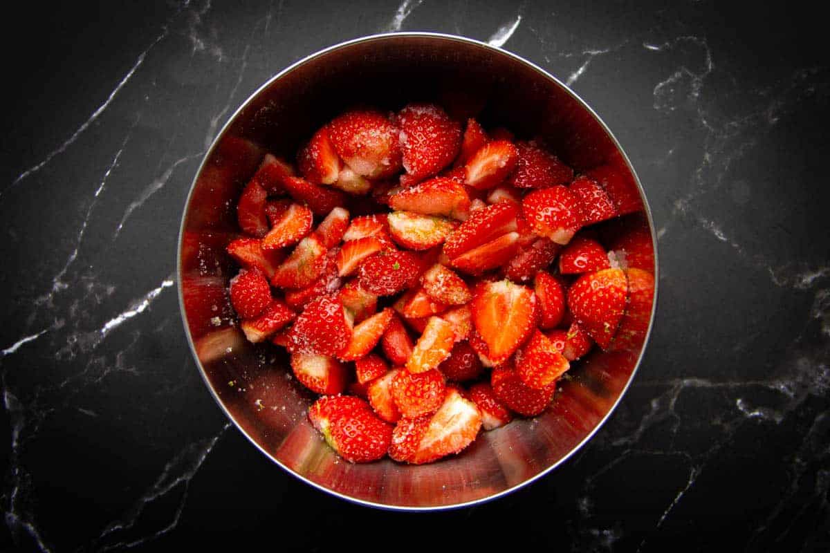 Curing the strawberries in sugar in a bowl.