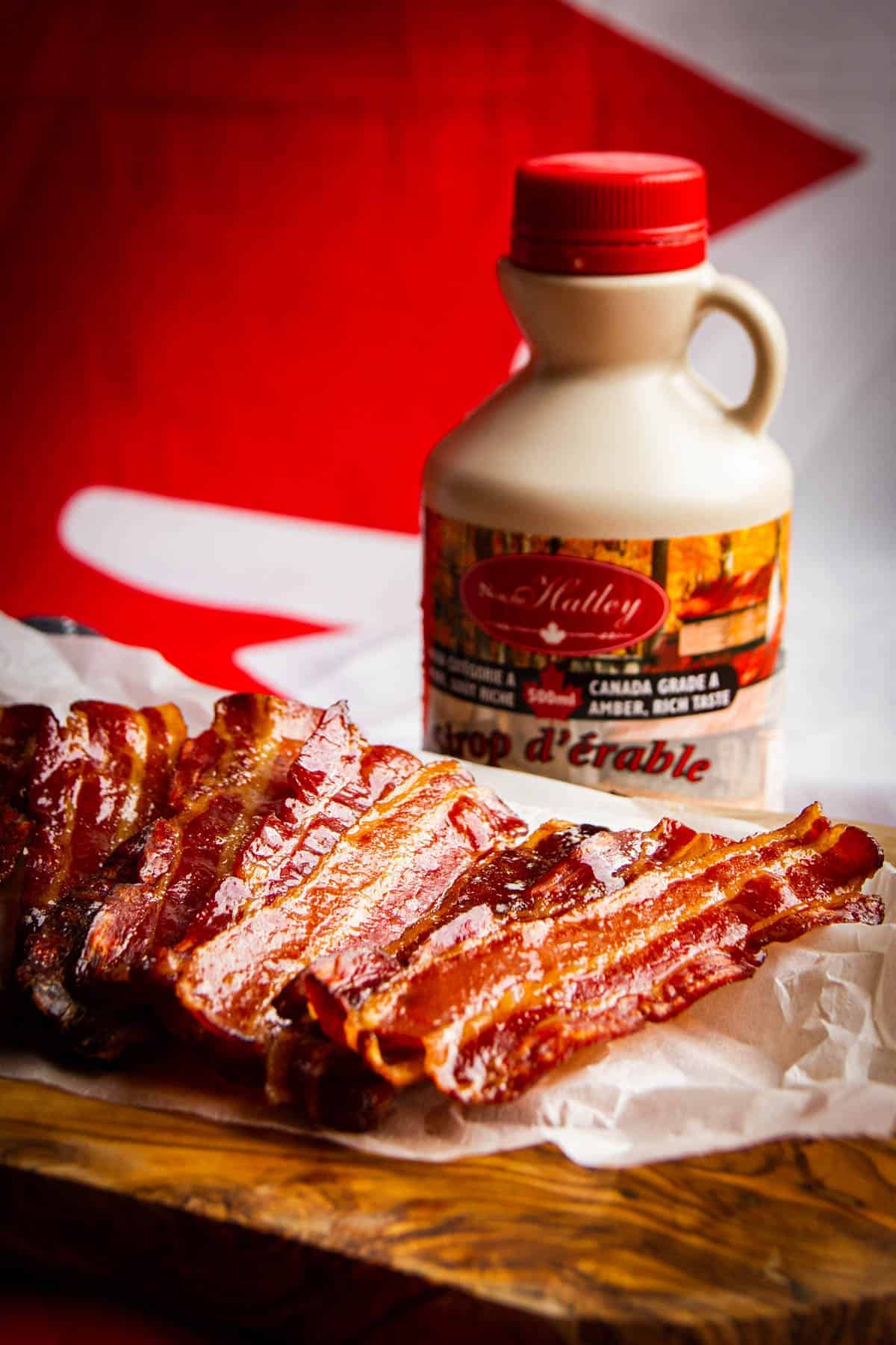 Maple bacon with a bottle of maple syrup in the background.