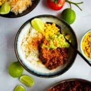 Sofritas in a bowl with guac, beans, corn and fresh lime.