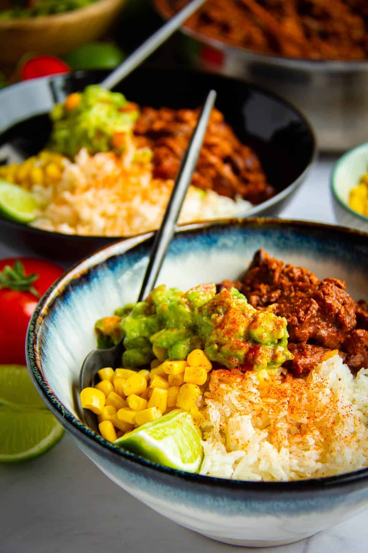 Sofritas in a bowl with guac, beans, corn and fresh lime.