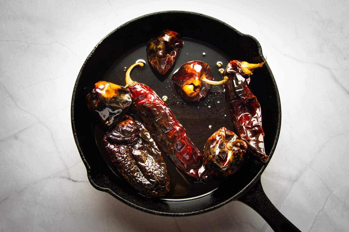 Toasting the dried peppers in oil.