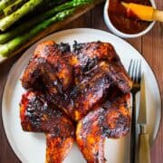 Grilled spatchcock chicken with bbq sauce and asparagus on the side.