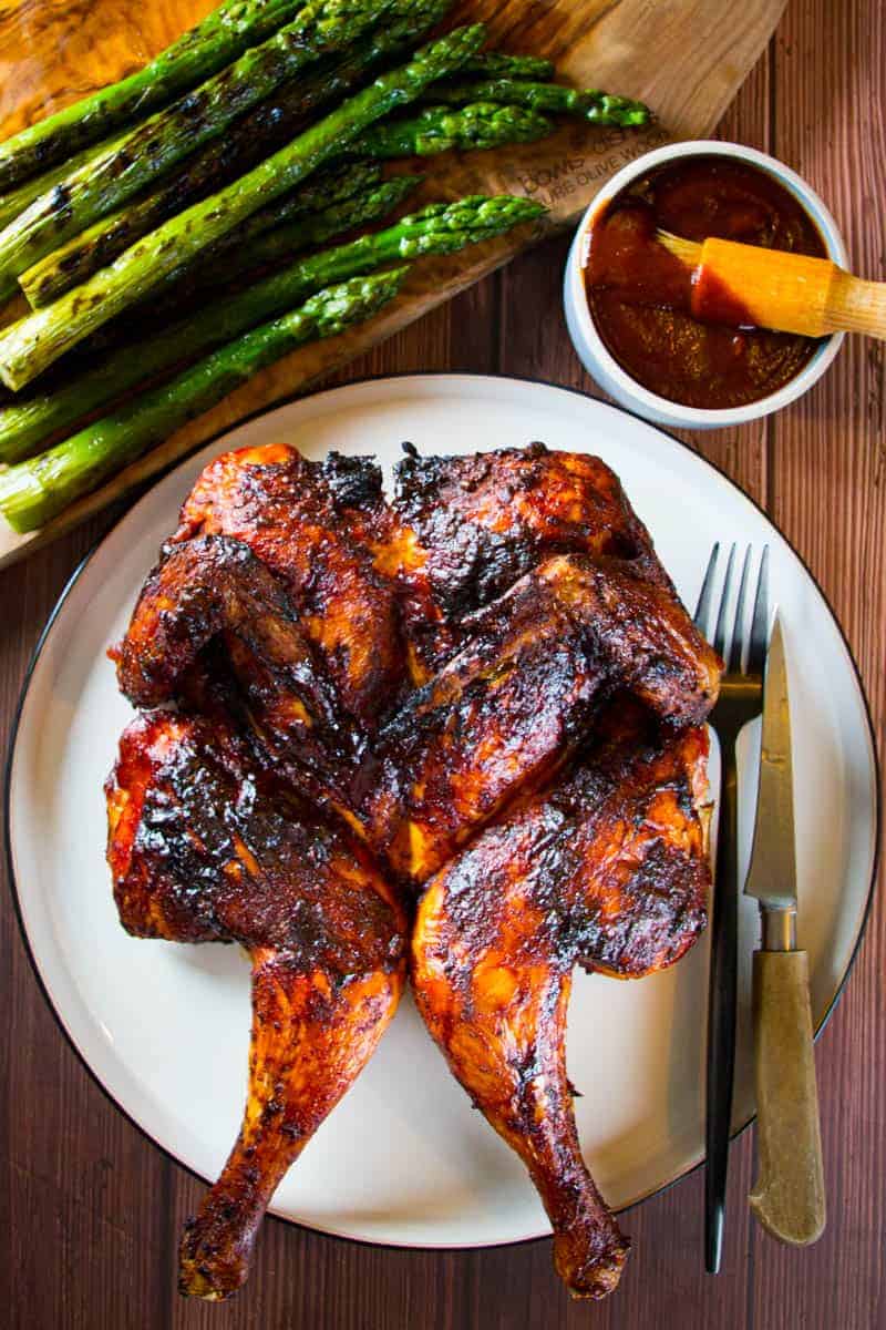 Grilled spatchcock chicken with bbq sauce and asparagus on the side.