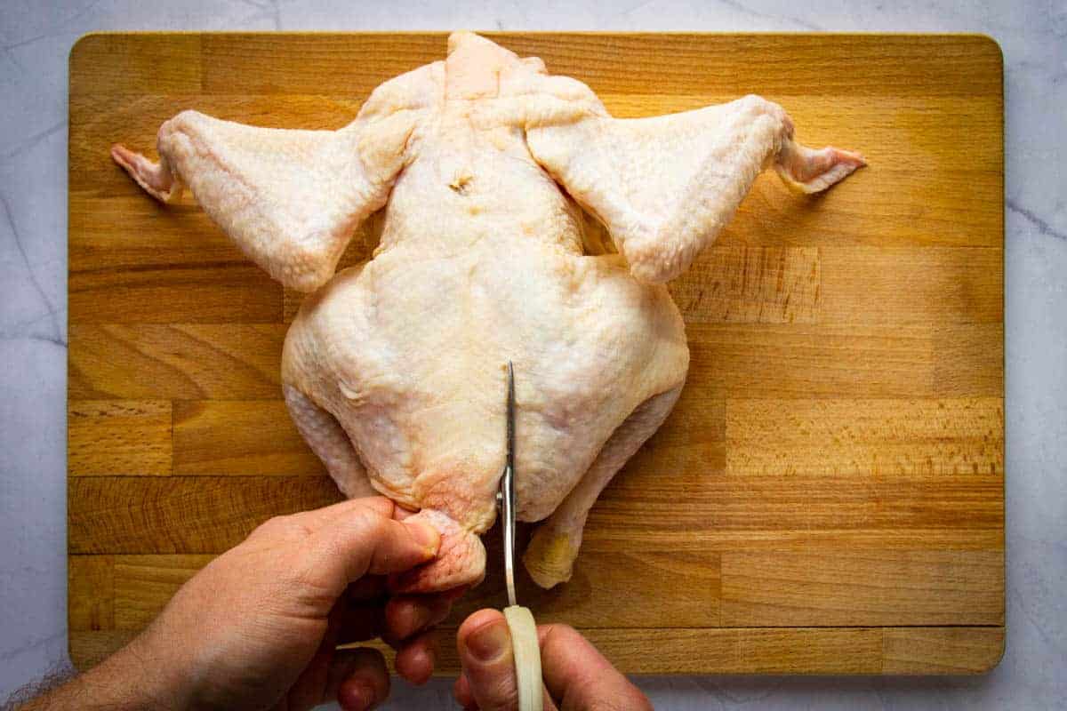 Cutting along the back of the chicken to remove the backbone.