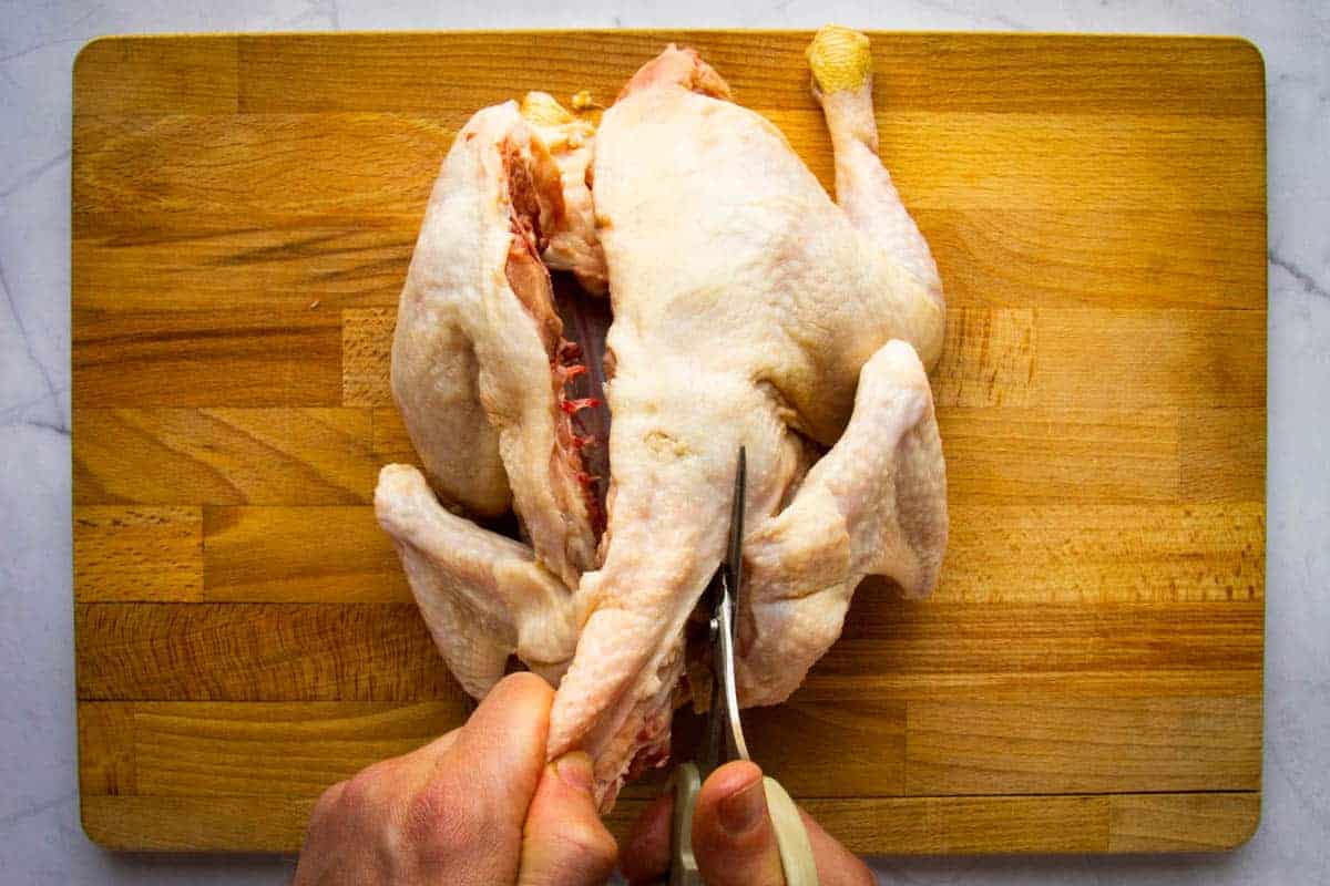 Removing the back bone from the chicken.
