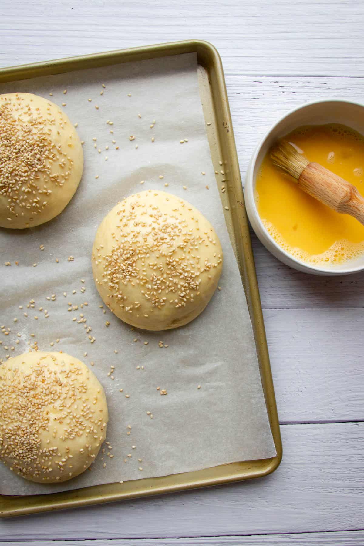 Adding the egg wash and sesame to the burger buns.