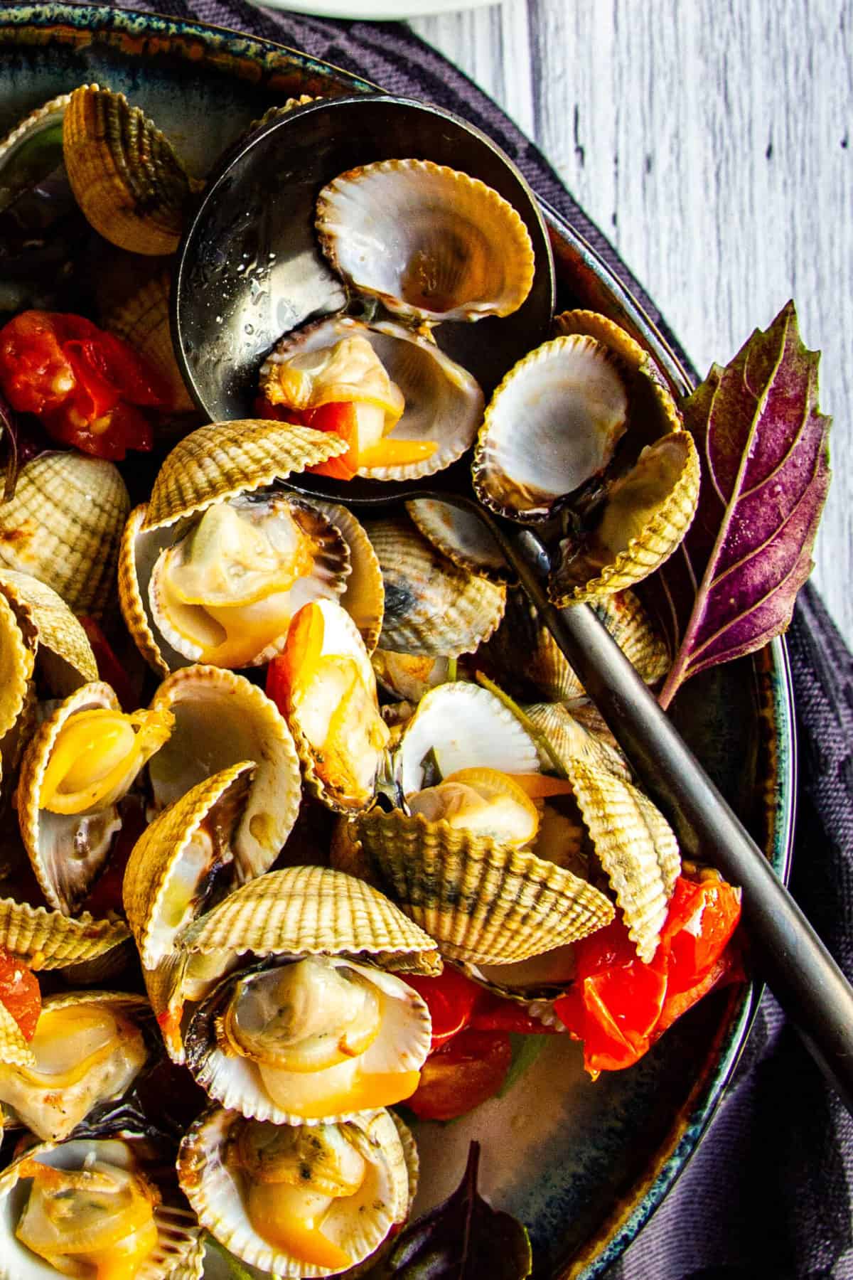 A close up shot of the cockles with a spoon inside.