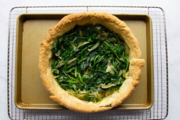 Adding the cooked spinach to the quiche.