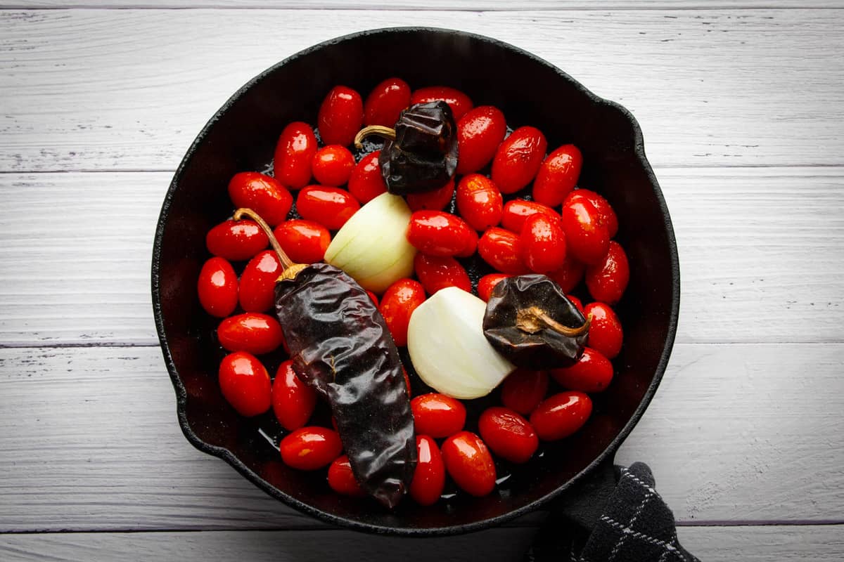 Cooking the cherry tomatoes, peppers and onions in the cast iron pan.