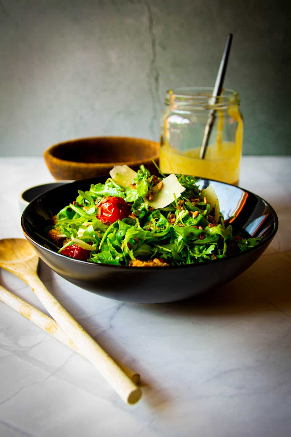 Rocket salad on the table with sunflower dressing in the background.