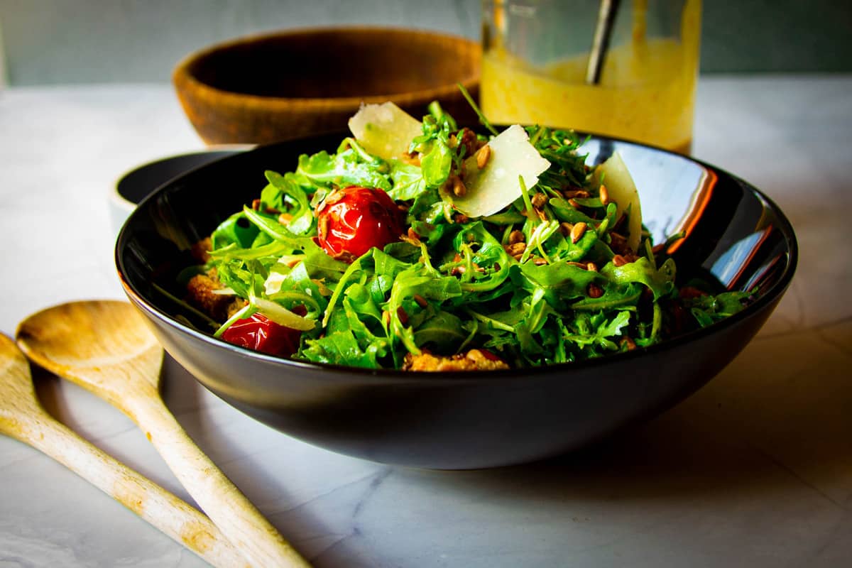 A rocket salad, sunflower dressing, croutons and sunflower seeds on the table.