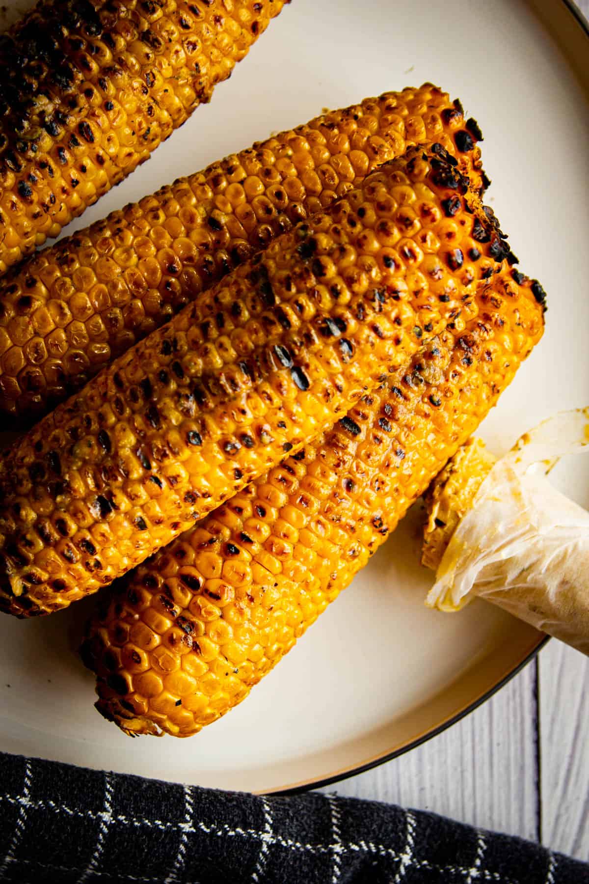 Roasted and charred corn on a plate with umami butter on the side.