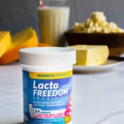 A bottle of Lacto Freedom supplements with milk products in the background.