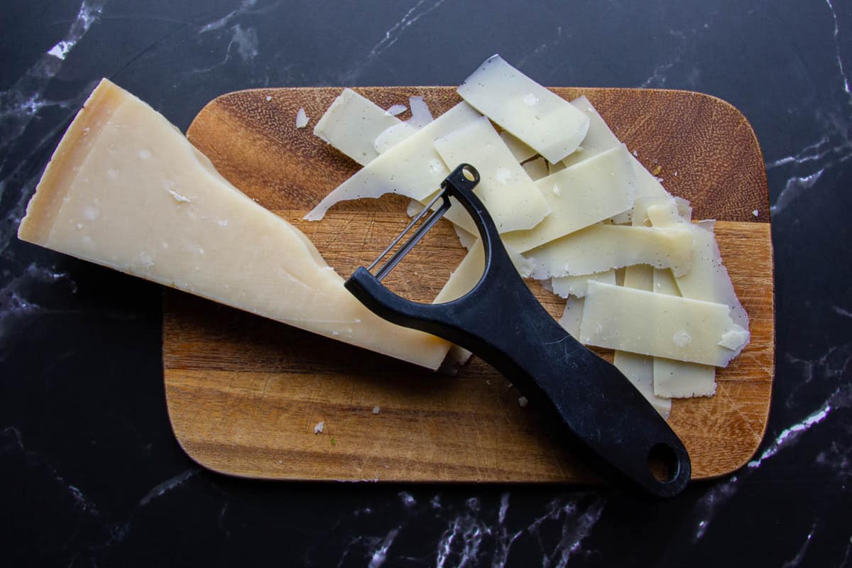 Slicing the cheese with a peeler.