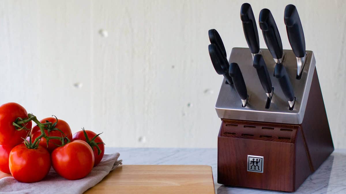 A henckel knife block with tomatoes in the background.