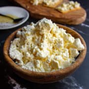 A bowl of whole milk ricotta on a black marble table.