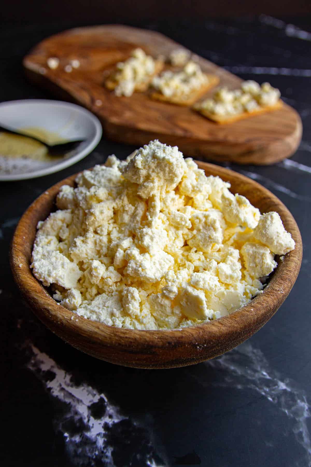 A bowl of whole milk ricotta on a black marble table.