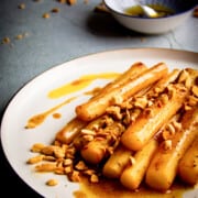 Braised black salsify on a plate with toasted almonds and brown butter.