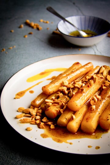 Braised black salsify on a plate with toasted almonds and brown butter.