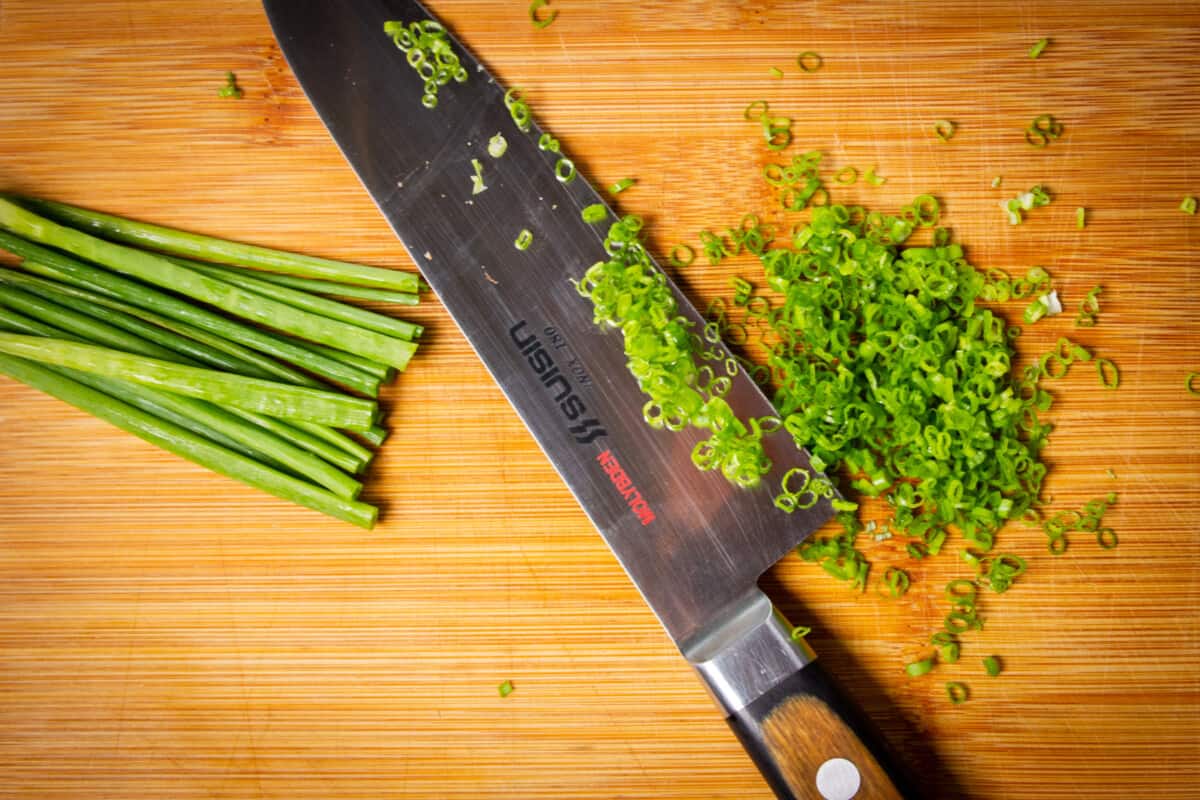 Slicing the chives finely on a cutting board.