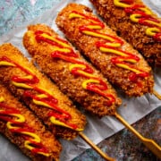 5 Korean corn dogs with ketchup and mustard drizzled over top.