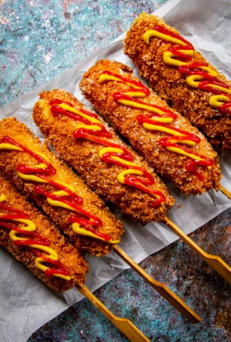 5 Korean corn dogs with ketchup and mustard drizzled over top.
