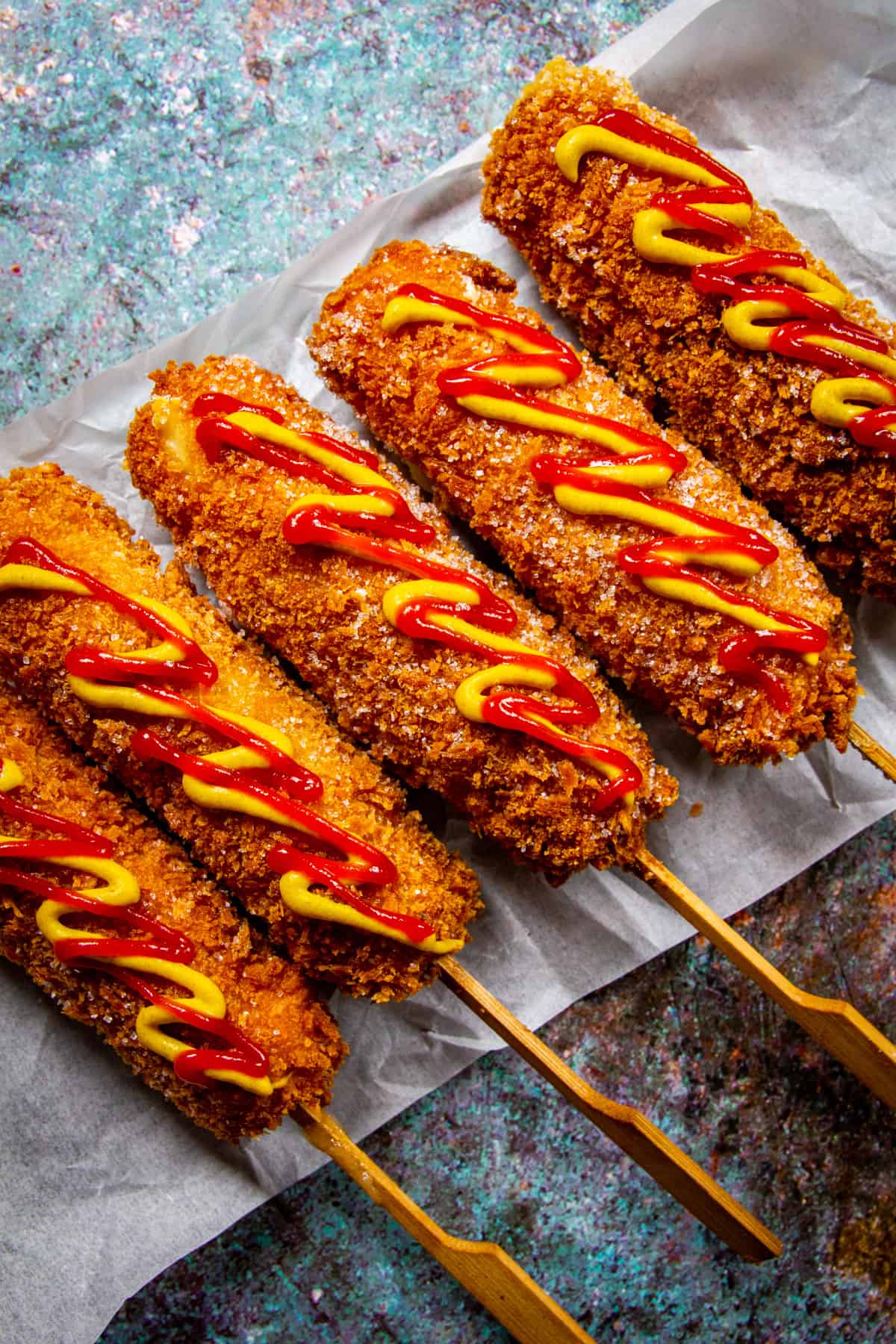 5 Korean corn dogs with ketchup and mustard drizzled over top.