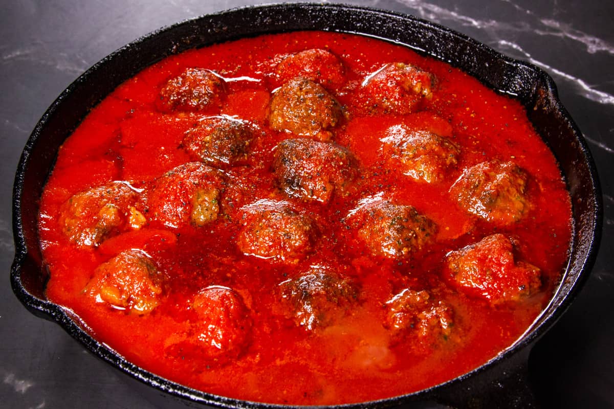 Adding the tomato passata to the meatballs.