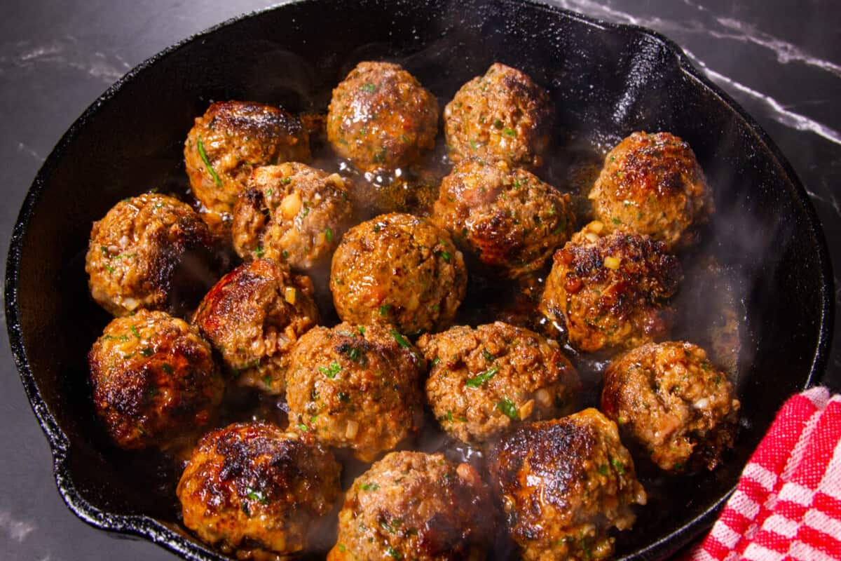 The browned meatballs in the cast iron pan.