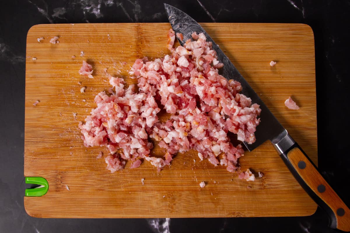 Chopping the bacon on a cutting board.