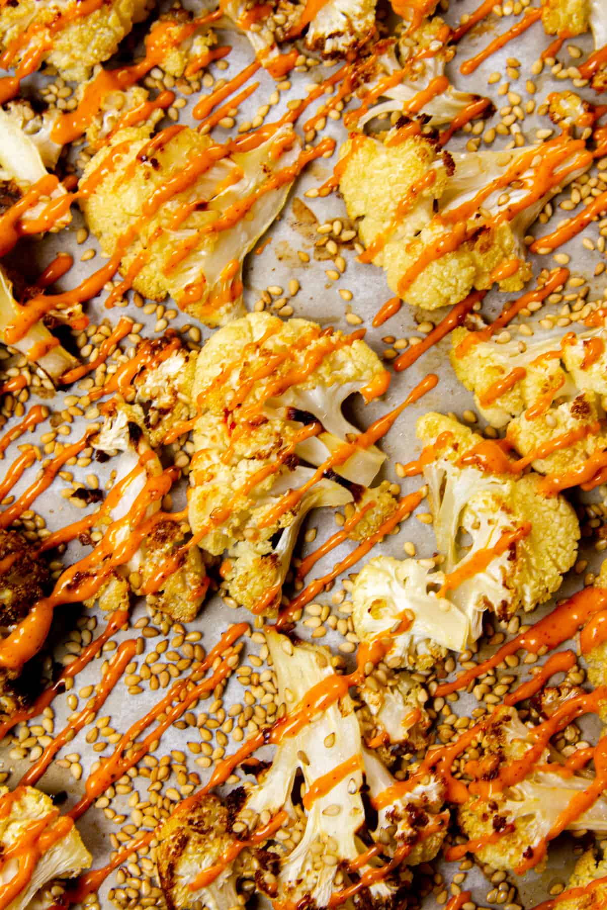 Roasted cauliflower florets with gochujang mayo on a sheet tray.