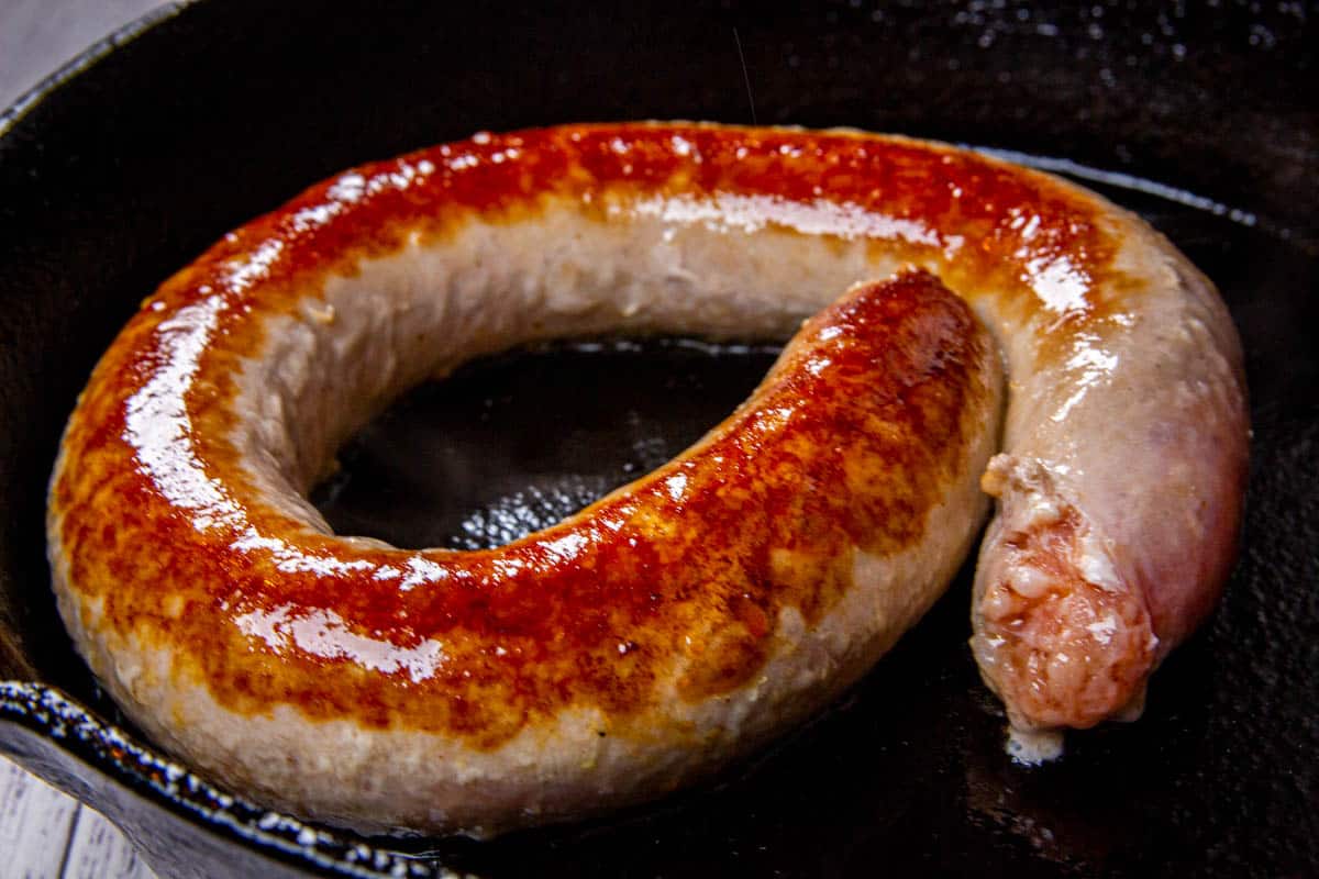Cooking sausages in a cast iron pan.