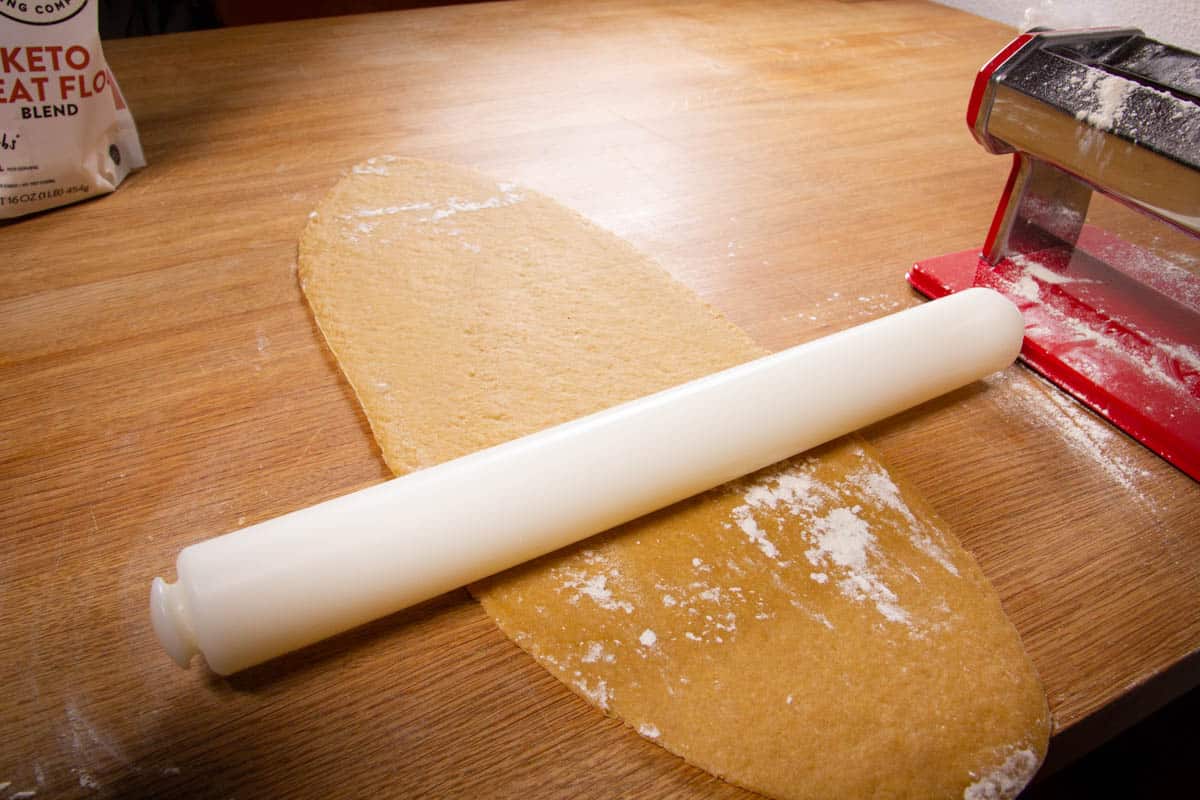 Rolling the pasta flat with the rolling pin.
