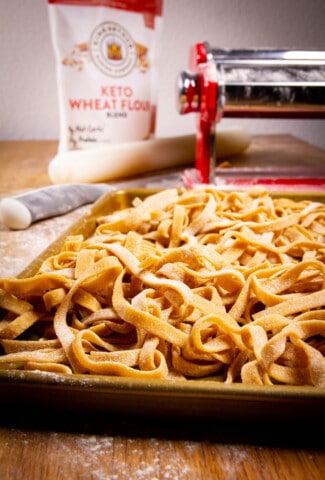 My keto pasta on a tray with the pasta machine the background.