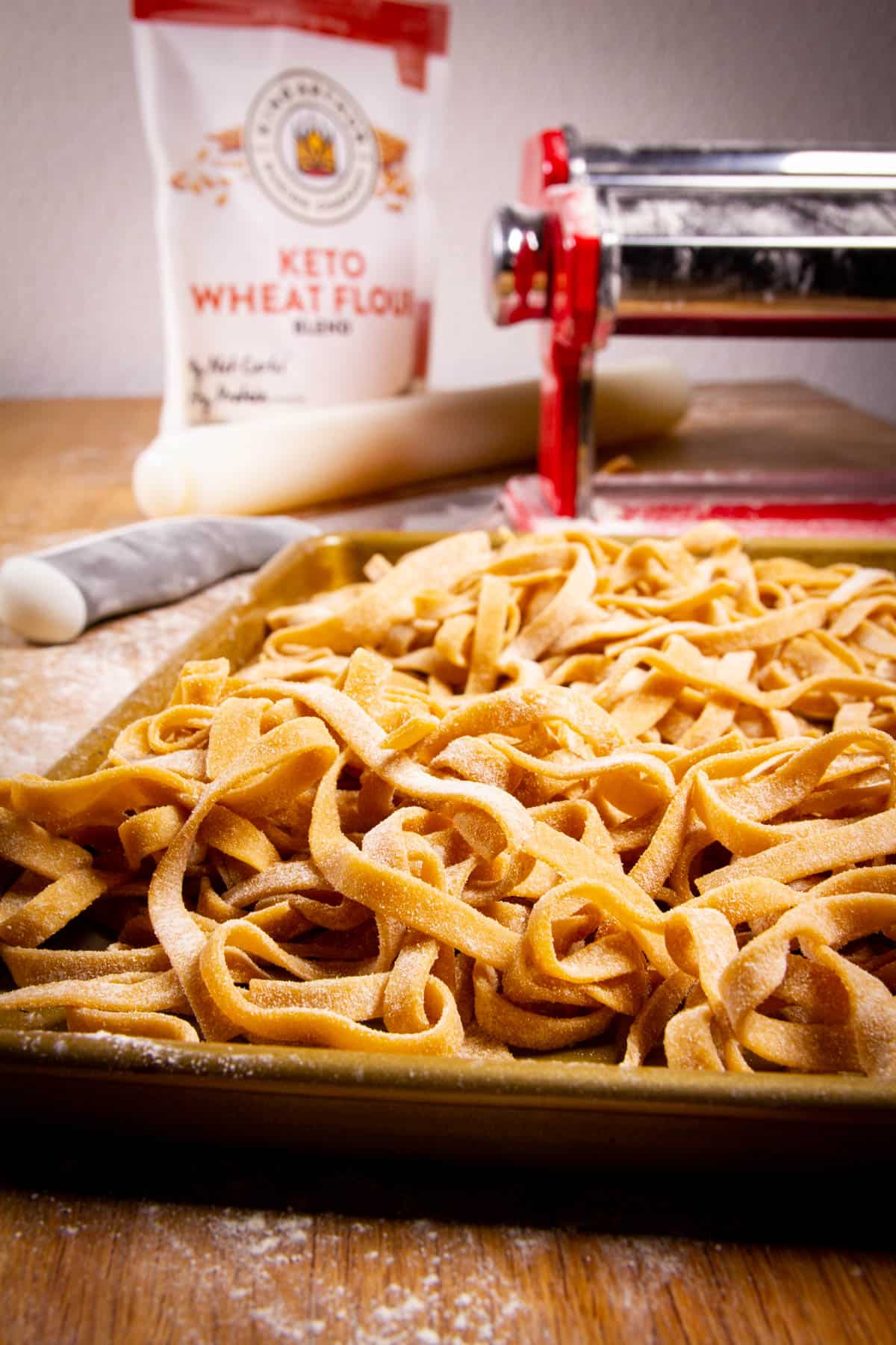 My keto pasta on a tray with the pasta machine the background.