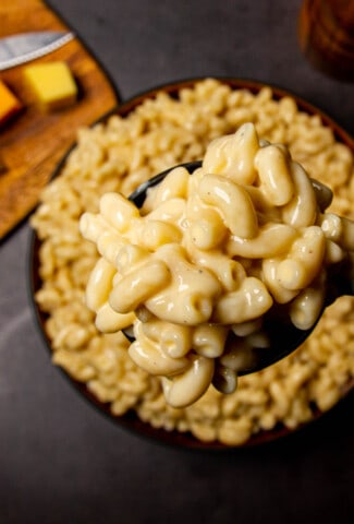 A close up shot of a very saucy and cheesy mac and cheese sauce on a spoon.