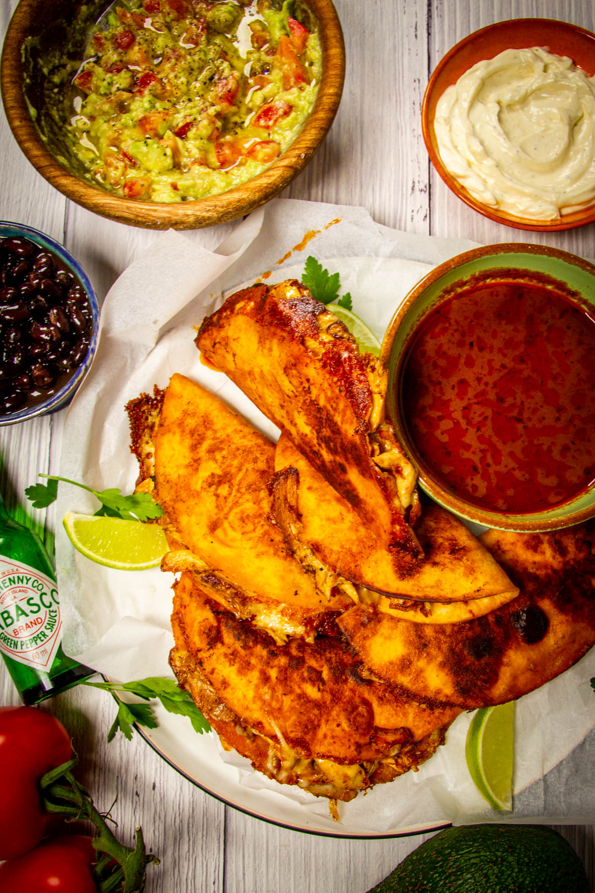 A top down shot of the finished chicken birria tacos on a plate with all the condiments around.