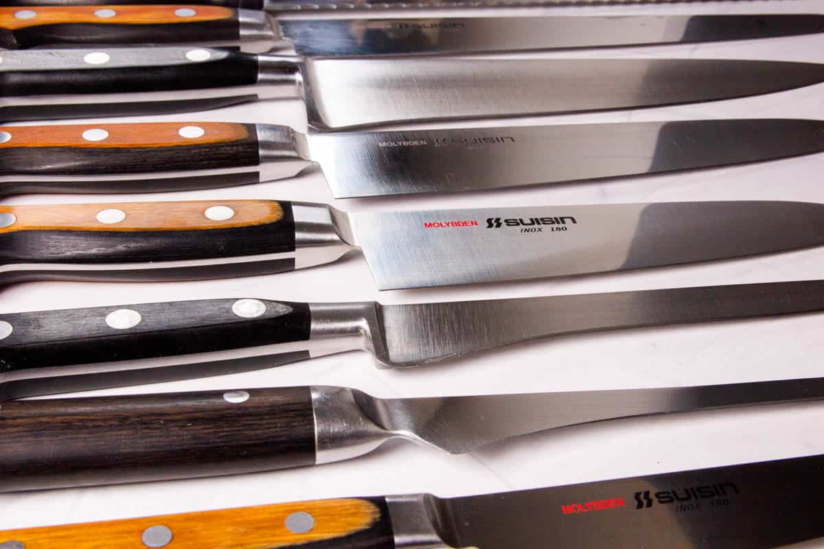 A collection of many knives laying on a table.