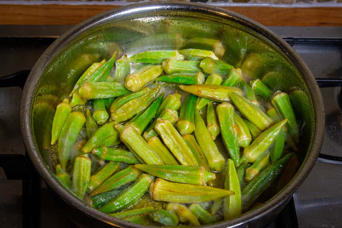 Frying the frozen okra in a pan with high sides.