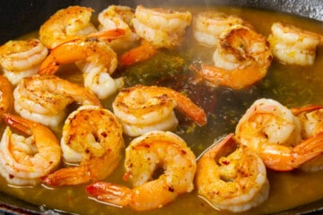 The starchy pasta water in the pan with the shrimp.