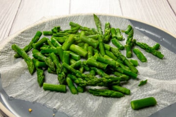 Drying the asparagus on a plate with paper towel.