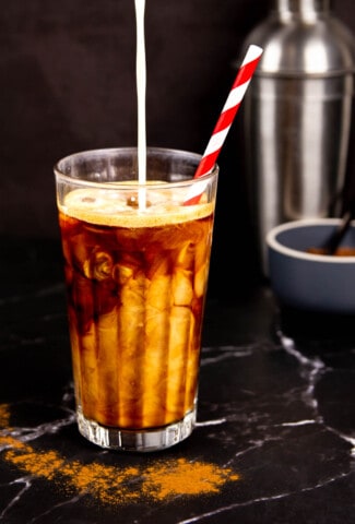 A Brown Sugar Oatmilk Shaken Espresso in a tall glass with a striped paper straw.