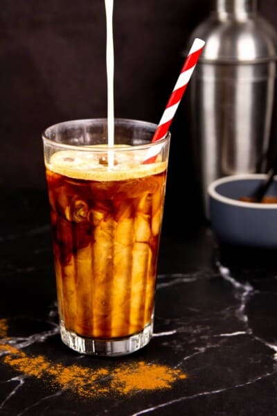 A Brown Sugar Oatmilk Shaken Espresso in a tall glass with a striped paper straw.