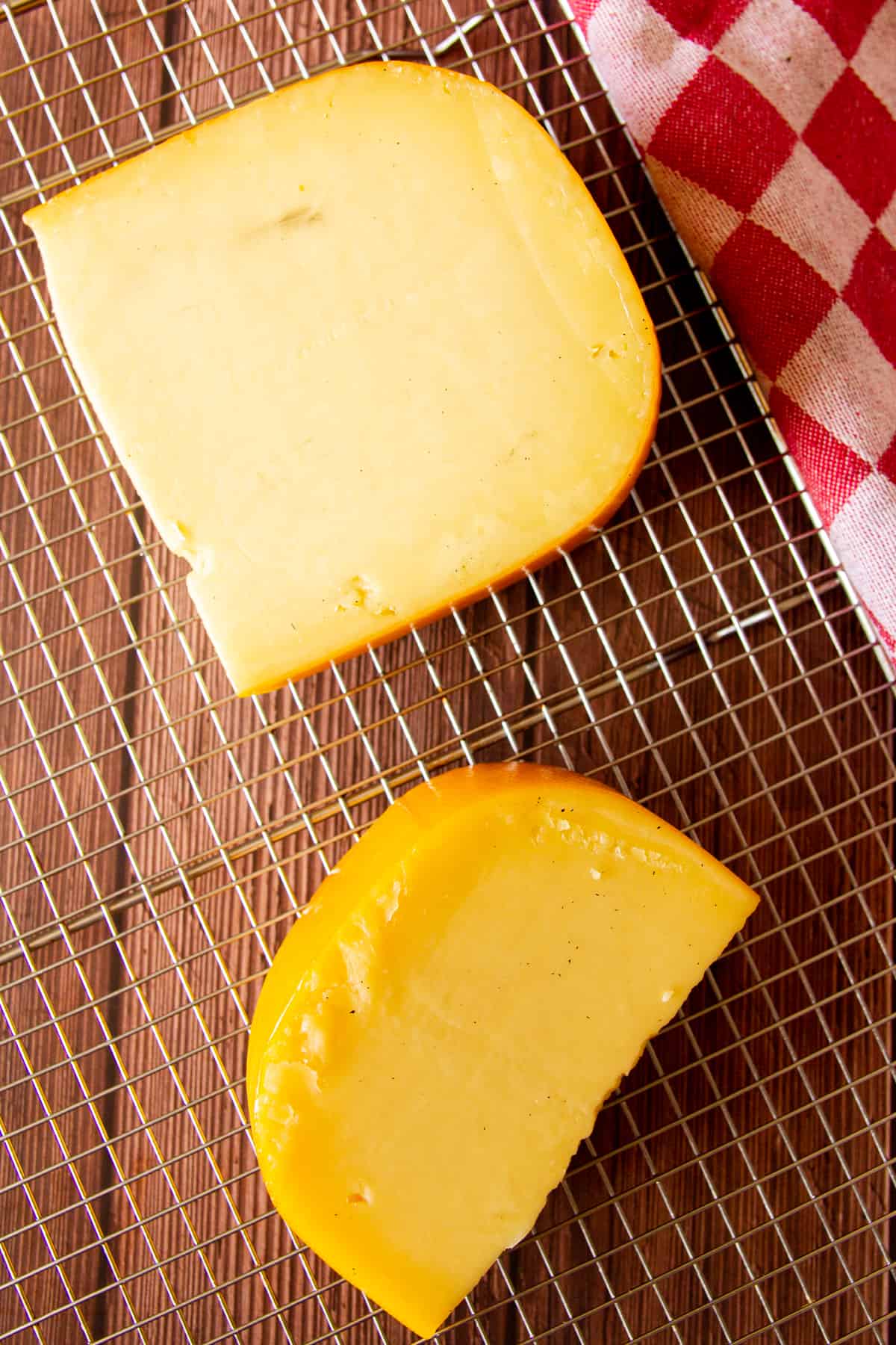 Two blocks of smoked gouda on a resting rack.