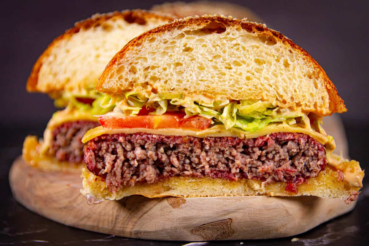 A close up of the burger sliced in half with a visible pink smoke ring.