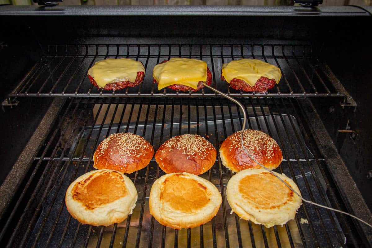 Buns on the grill and cheese on the burgers.